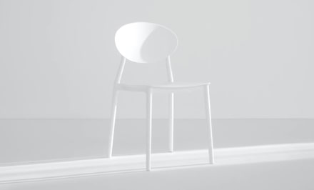 A single white chair in a bright, minimalist setting.