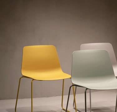 Three chairs of different colors arranged with one in the front and two in the back.